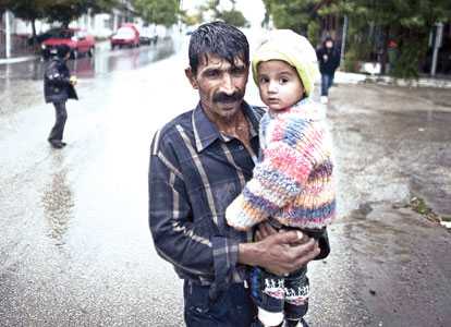 This file photo shows a Pakistani man holding his daughter in Nea Vissa, Greece. A new report calls for the rigorous analysis of core capacities of countries to manage migration effectively and identify gaps and priorities for the future.