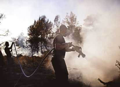 Israeli firefighters douse a burning area in the village of Ussafiya in Carmel forest. AFP photo Israeli firefighters douse a burning area in the village of Ussafiya in Carmel forest. AFP photo