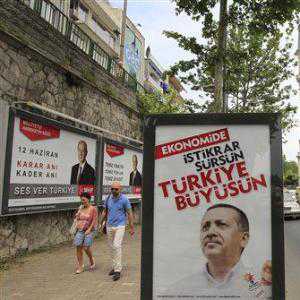 Pedestrians walk between election billboards as Dolmabahce Mosque is seen in the background in Istanbul, Turkey, on Friday, June 10, 2011