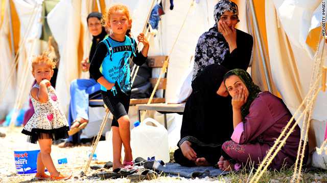 t1larg.syria.refugees.afp.gi Syrian refugees sit in front of their tents on June 18 in the southern part of Turkey.