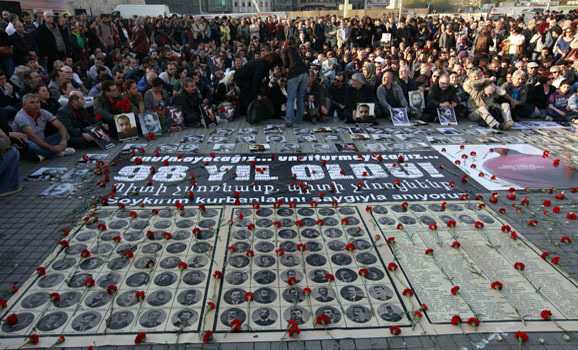 Human rights activists sit behind pictures of Armenian victims at Taksim square in central Istanbul