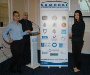Polis toplantılarına konuşmacı olarak S.A.M.U.R.A.I. panosu ile katılan Polis Dernekleri Federasyonu Başkanı Halil Hüseyin, Metropolitan Polisi’nin melekleri (Cadet) olarak tanımlanan Türk kökenli gençlerden Neslihan Kaygusuz (solda) ve Zeynep Güzeladlı gençlerimizle.
